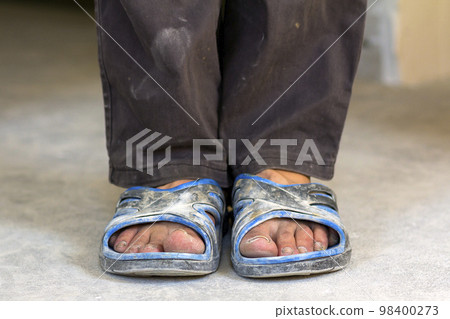 Feet of a person in old dirty clothes and shoes Feet of a person in old dirty clothes and shoes 98400273