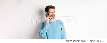 Technology concept. Joyful man enjoying phone call, talking on smartphone and smiling, standing in casual shirt over white background Technology concept. Joyful man enjoying phone call, talking on smartphone and smiling, standing in casual shirt over white background 98400312