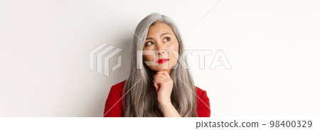 Close up of thoughtful asian business woman looking at upper left corner, thinking or making choice, standing over white background 98400329