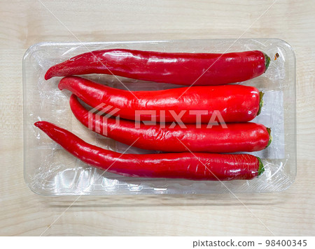 Red chilli spur peppers in plastic pack on the table Red chilli spur peppers in plastic pack on the table 98400345