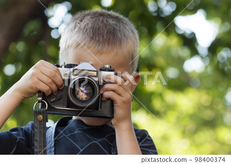 Cute little happy boy with vintage photo camera outdoors 98400374