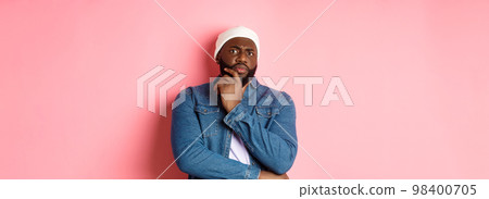 Doubtful african american man staring at camera with disbelief, standing skeptical and thinking, pink background 98400705
