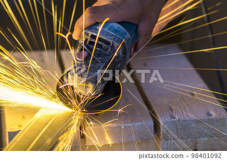 Close-up of worker hands cutting metal with grinder. Sparks while grinding iron. Low depth of focus Close-up of worker hands cutting metal with grinder. Sparks while grinding iron. Low depth of focus 98401092