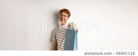 Funny handsome boyfriend giving shopping bag with gift, congratulate with valentines day and smiling, standing over white background 98401118