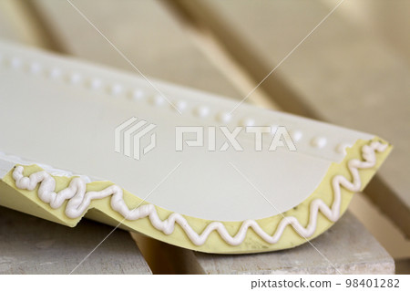 Close-up detail of decoration molding with glue adhesive before installation in interior renovation. 98401282