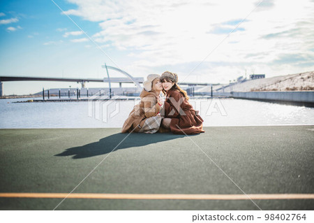 婦女們在俯瞰大海的港口愉快地聊天 婦女們在俯瞰大海的港口愉快地聊天 98402764