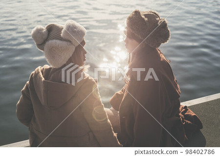 婦女們在俯瞰大海的港口愉快地聊天 98402786