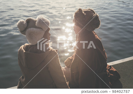 婦女們在俯瞰大海的港口愉快地聊天 98402787