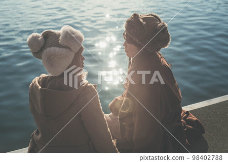 婦女們在俯瞰大海的港口愉快地聊天 98402788
