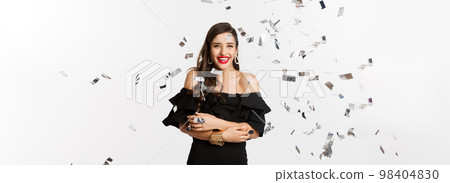 Happy woman celebrating winter holidays, smiling cheerful, partying on New Year with confetti, standing over white background 98404830