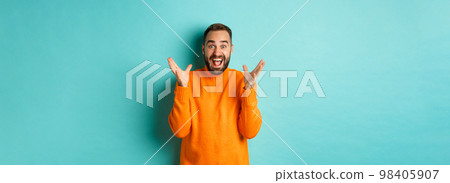 Image of excited and happy bearded man, shaking hands and smiling amazed, telling big news, standing over light blue background Image of excited and happy bearded man, shaking hands and smiling amazed, telling big news, standing over light blue background 98405907