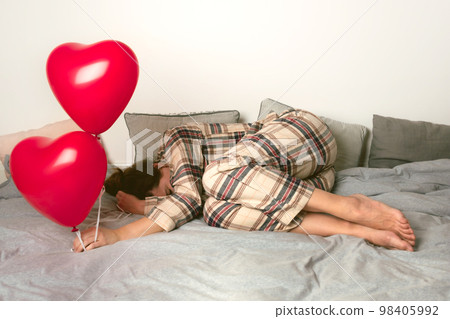 Depressed woman with an inflatable balloon on Valentine's Day. Front view. Depressed woman with an inflatable balloon on Valentine's Day. Front view. 98405992
