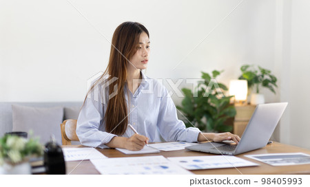 Beautiful young asian woman watching live video or video call of teacher teaching on laptop in her home, Take notes of important conversations and messages during the teacher's teaching. Beautiful young asian woman watching live video or video call of teacher teaching on laptop in her home, Take notes of important conversations and messages during the teacher's teaching. 98405993