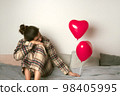 Depressed woman with an inflatable balloon on Valentine's Day. Front view.  98405995