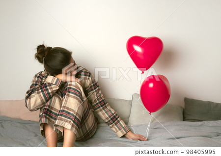 Depressed woman with an inflatable balloon on Valentine's Day. Front view.  98405995