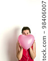 A woman holds an inflatable balloon in the shape of a pink heart. Birthday and valentine's day concept. Front view. 98406007