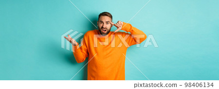 Angry man pointing at head, are you crazy gesture, scolding someone, standing over light blue background 98406134