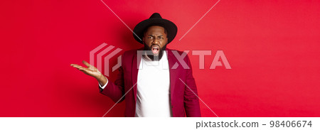 Angry and confused Black man arguing, shouting at camera and raising hand bothered, cant understand something, red background Angry and confused Black man arguing, shouting at camera and raising hand bothered, cant understand something, red background 98406674