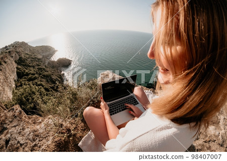 Woman sea laptop. Business woman working on laptop by sea at sunset. Close up on hands of pretty lady typing on computer outdoors summer day. Freelance, digital nomad, travel and holidays concept. 98407007