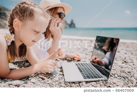 Woman sea laptop. Business woman with daughter, working on lapto Woman sea laptop. Business woman with daughter, working on lapto 98407009
