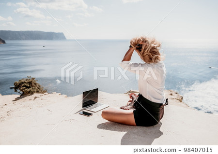 Woman sea laptop yoga. Business woman freelancer in yoga pose working over blue sea beach at laptop and meditates. Girl relieves stress from work. Freelance, digital nomad, travel and holidays concept Woman sea laptop yoga. Business woman freelancer in yoga pose working over blue sea beach at laptop and meditates. Girl relieves stress from work. Freelance, digital nomad, travel and holidays concept 98407015