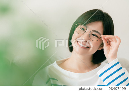 Young woman wearing glasses in the living room Young woman wearing glasses in the living room 98407499