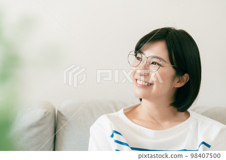 Young woman wearing glasses in the living room Young woman wearing glasses in the living room 98407500