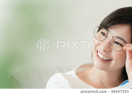 Young woman wearing glasses in the living room Young woman wearing glasses in the living room 98407503