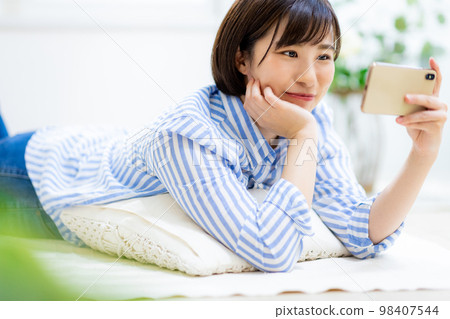 A woman looks at her smartphone while sleeping A woman looks at her smartphone while sleeping 98407544