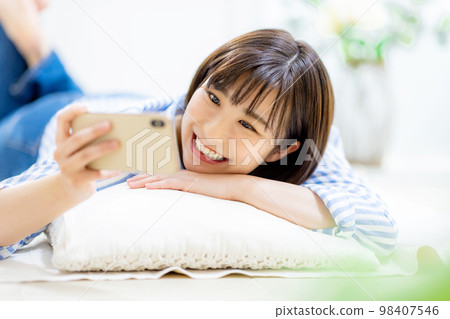 Young woman is operating a smartphone Young woman is operating a smartphone 98407546