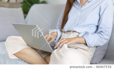 Woman using laptop to work or do homework at home with smiling face in her living room, Creating happiness at work with a smile, Live performance or video call with laptop, Work from home. Woman using laptop to work or do homework at home with smiling face in her living room, Creating happiness at work with a smile, Live performance or video call with laptop, Work from home. 98407559