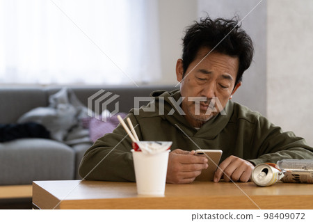 A man in his 50s who is depressed while looking at a smartphone A man in his 50s who is depressed while looking at a smartphone 98409072