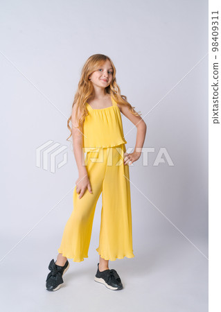 Smiling blonde girl in yellow summer suit posing isolated on light gray 98409311
