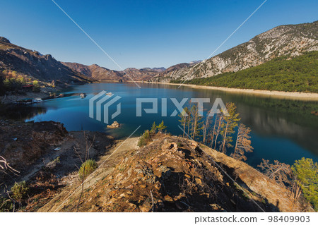 Dam lake in Green Canyon. Beatiful View to Taurus Mountains and turquoise water. Coniferous forest with green pine trees and a road stretching into the distance. Manavgat, Turkey. Dam lake in Green Canyon. Beatiful View to Taurus Mountains and turquoise water. Coniferous forest with green pine trees and a road stretching into the distance. Manavgat, Turkey. 98409903