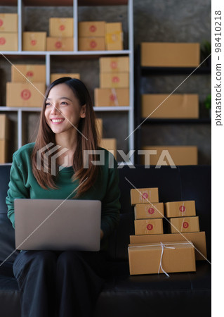 Portrait of Asian young woman SME working with a box at home. small business owner entrepreneur SME and delivery concept Portrait of Asian young woman SME working with a box at home. small business owner entrepreneur SME and delivery concept 98410218