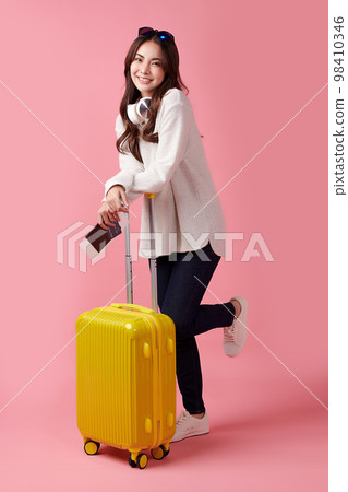 Travel concept. Beautiful Young Asian female tourist sit with suitcase, on pink background. Travel concept. Beautiful Young Asian female tourist sit with suitcase, on pink background. 98410346