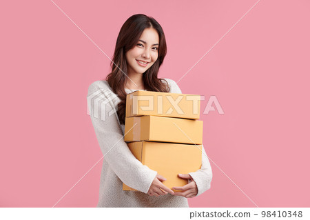 Beautiful Young Asian woman holding parcel box isolated on pink background, Delivery courier and shipping service concept. Beautiful Young Asian woman holding parcel box isolated on pink background, Delivery courier and shipping service concept. 98410348
