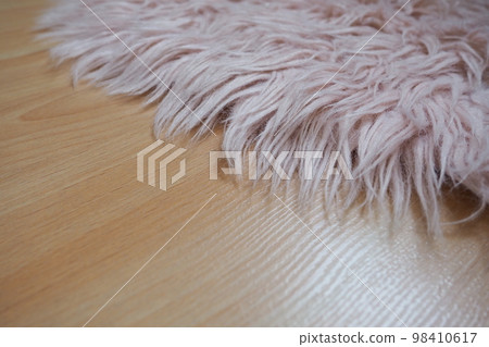 Long pile rug in pink on a beige laminate floor. Feminine interior for a room or bedroom of a girl or woman. Interior design in pink tones. Flooring is laminate. The role of dust mites in allergies. 98410617