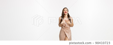 Christmas party and celebration concept. Glamour woman in elegant dress, looking touched and thankful, laughing coquettish, white background 98410723