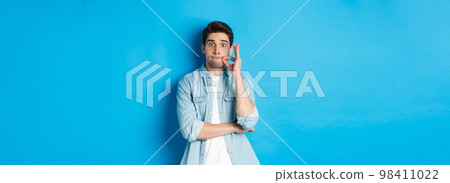 Adult man zipping mouth, promise keep secret, making a seal on lips and standing over blue background Adult man zipping mouth, promise keep secret, making a seal on lips and standing over blue background 98411022
