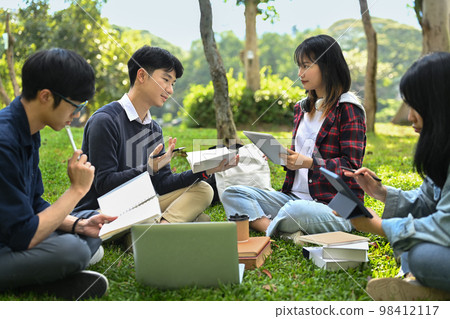 Group of happy young friends sitting in college campus and talking. University, youth lifestyle and friendship concept 98412117