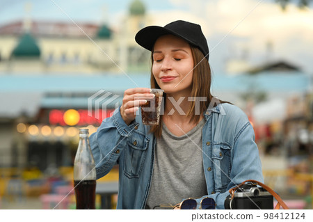 Young hipster woman in jean jacket drinking cola while sitting at street market in Chiang Mai Northern Thailand Young hipster woman in jean jacket drinking cola while sitting at street market in Chiang Mai Northern Thailand 98412124