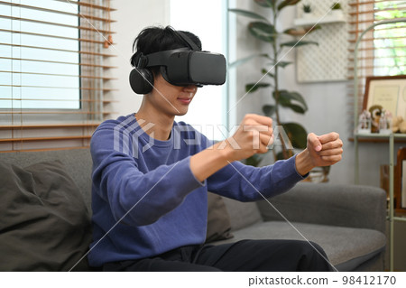Young Asian man enjoy playing a driving simulation video game on virtual reality glasses 98412170