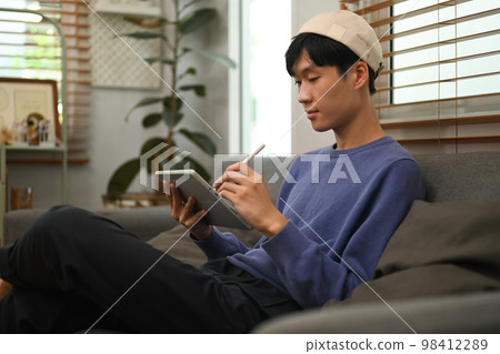 Image of stylish man browsing Internet or checking social networks on digital tablet. People and technology concept Image of stylish man browsing Internet or checking social networks on digital tablet. People and technology concept 98412289