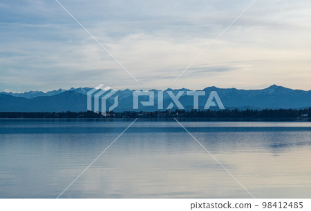 Starnberger See, Germany - December 30th 2022: Flat water surface of the lake in front of the alpine ridge 98412485