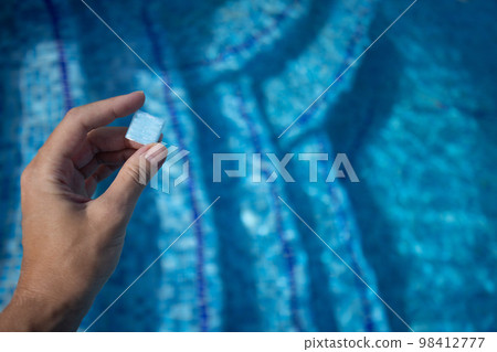 Hand holding small tile from floor of swimming pool. Design of the swimming pool. 98412777