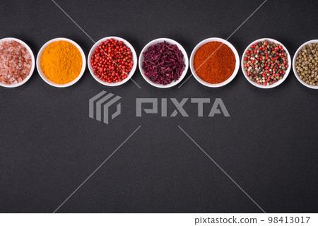 Composition consisting of variations of spices in white bowls and metal spoons 98413017