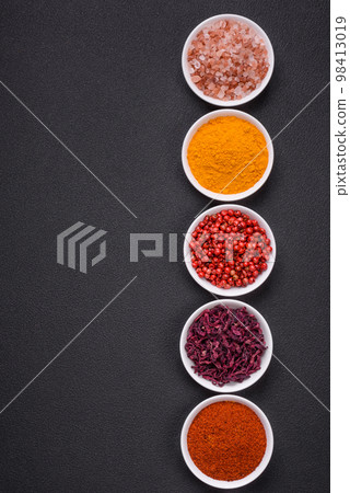 Composition consisting of variations of spices in white bowls and metal spoons 98413019