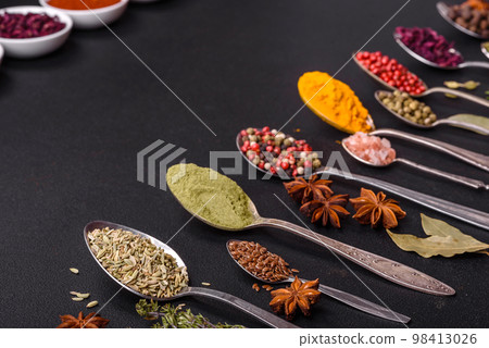 Composition consisting of variations of spices in white bowls and metal spoons 98413026