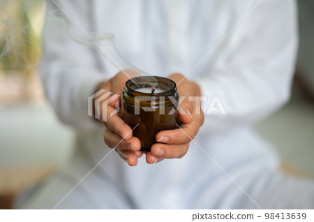 Woman in white clothes with mock up candle in jar in hands Woman in white clothes with mock up candle in jar in hands 98413639
